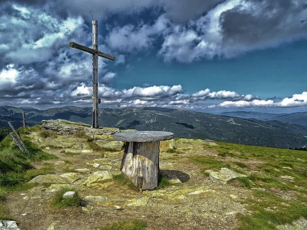 Gipfelkreuz über einem weiten Bergrücken